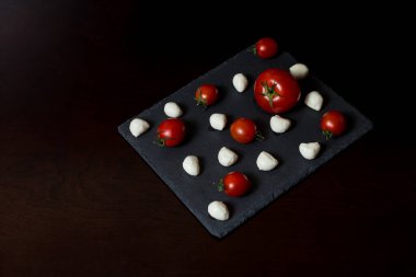 Yemek Geçmişi. Küçük mozzarella peyniri topları ve taş tabakta kiraz domatesleri. Üst Manzara. menü tasarımı kavramı.
