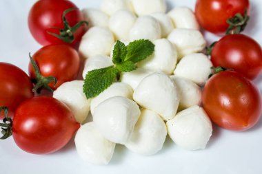 Beyaz tabakta mini mozzarella peyniri ve vişneli domates topları. menü tasarımı kavramı.