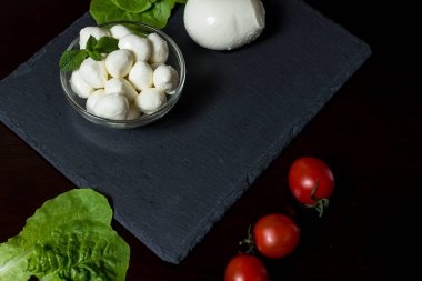 Yemek Geçmişi. Fesleğen yaprağı, marul, domates ve acı biberli büyük ve küçük mozzarella peyniri topları. Eski arka planda. Bedava fotokopi. Üst Manzara. menü tasarımı kavramı