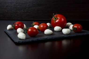 Yemek Geçmişi. Küçük mozzarella peyniri topları ve taş tabakta kiraz domatesleri. Üst Manzara. menü tasarımı kavramı.