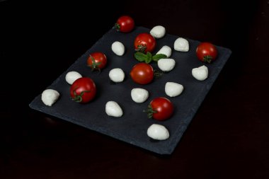 Yemek Geçmişi. Küçük mozzarella peyniri topları ve taş tabakta kiraz domatesleri. Üst Manzara. menü tasarımı kavramı.