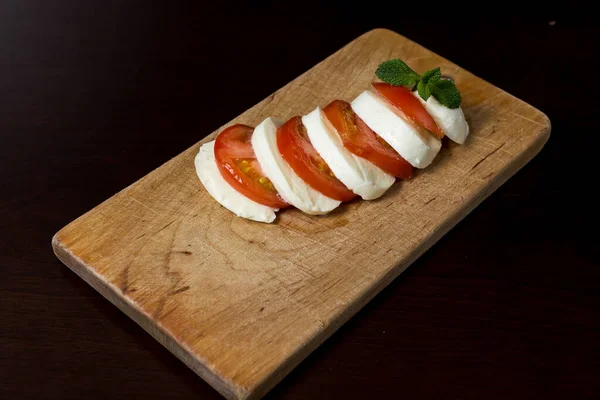 食物背景 切碎的莫扎拉奶酪和切碎的西红柿放在一个木制盘子里 上面有罗勒叶 顶部视图 菜单设计概念 — 图库照片