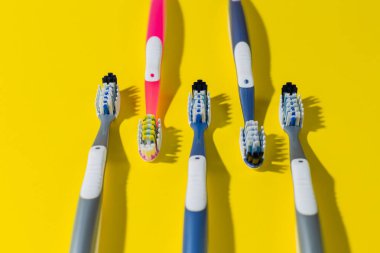 Sarı arka planda beş farklı renkte diş fırçası var. Caries önleme. Diş sağlığı kliniği. Dişçilik. diş sağlığı.