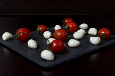 Yemek Geçmişi. Küçük mozzarella peyniri topları ve taş tabakta kiraz domatesleri. Üst Manzara. menü tasarımı kavramı.