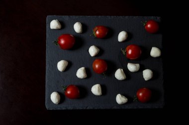 Yemek Geçmişi. Küçük mozzarella peyniri topları ve taş tabakta kiraz domatesleri. Üst Manzara. menü tasarımı kavramı.