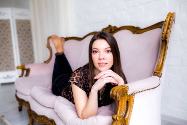 Güzel kız kanepede uzanıyor ve gülümseyen kameraya bakıyor..