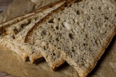 Paket kağıdına dilimlenmiş taze pişmiş ekmek dilimi. Ahşap masa, kağıt, fırın ekmeği..