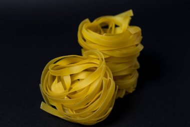 Koyu arkaplanda çiğ tagliatelle makarna. Reklam afişi. Metin için boşluk, geniş görünüm.