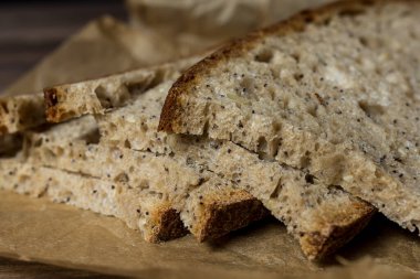  Paket kağıdına dilimlenmiş taze pişmiş ekmek dilimi. Ahşap masa, kağıt, fırın ekmeği..