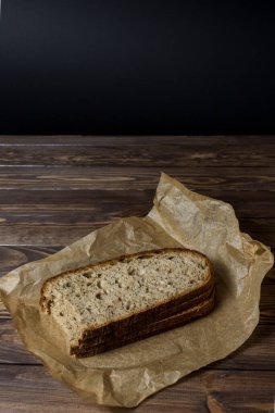  Paket kağıdına dilimlenmiş taze pişmiş ekmek dilimi. Ahşap masa, kağıt, fırın ekmeği..