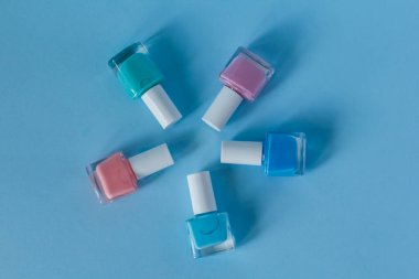 çok renkli tırnak cilası mavi arka planda bir daire oluşturur. Manikür salonu. Manikür ve pedikür. reklam afişi