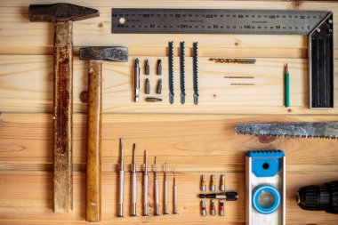 Marangozluk işi. Mobilya üretimi. El işi. Hafif ahşap arka plan. Ahşap doku. İki çekiç, bir matkap, bir kalem, bir demir testeresi.