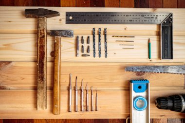Marangozluk işi. Mobilya üretimi. El işi. Hafif ahşap arka plan. Ahşap doku. İki çekiç, bir matkap, bir kalem, bir demir testeresi.