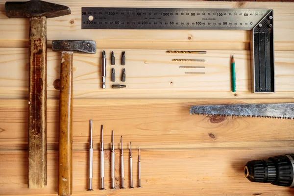 Marangozluk işi. Mobilya üretimi. El işi. Hafif ahşap arka plan. Ahşap doku. İki çekiç, bir matkap seti, bir kalem, bir demir köşe, bir demir testeresi, bir tornavida. Reklam afişi. Blog için fotoğraf. metin için yer.