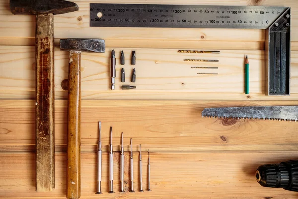 Marangozluk işi. Hafif ahşap arka plan. Ahşap doku. İki çekiç, bir matkap seti, bir kalem, bir demir köşe, bir demir testeresi, bir tornavida. Reklam afişi. Blog için fotoğraf. metin için yer.
