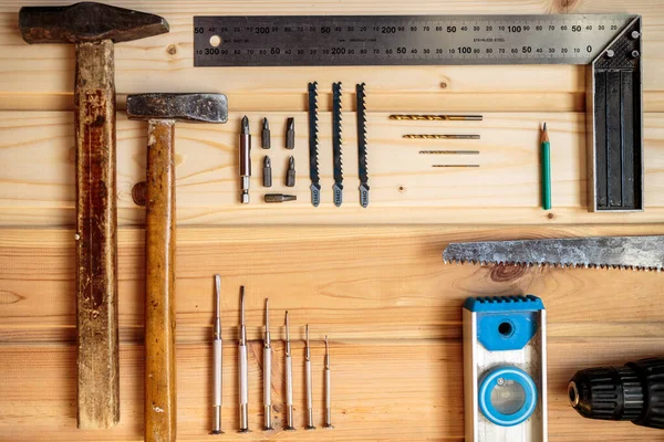 Marangozluk işi. Mobilya üretimi. El işi. Hafif ahşap arka plan. Ahşap doku. İki çekiç, bir matkap, bir kalem, bir demir testeresi.