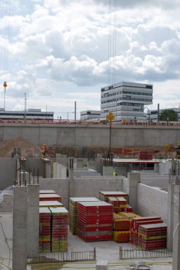 Bulutlu gökyüzünün altında, beyaz modern binanın önünde beton temeli olan inşaat alanı