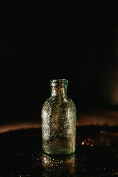 Nasse Kleine Flasche Mit Wassertropfen Auf Dunklem Hintergrund — Stockfoto