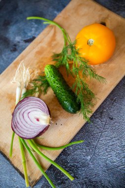 Mutfak tahtasındaki sebzeler. Soğan, sarı domates ve salatalık.