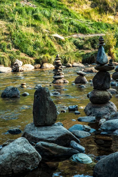 balanced Zen rock art tall stack of stones in flowing water of mountain stream at hot springs
