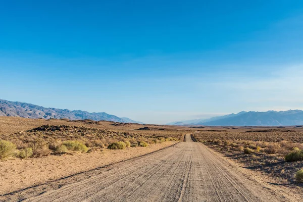 沙漠景观中的土路走向遥远的山脉 — 图库照片