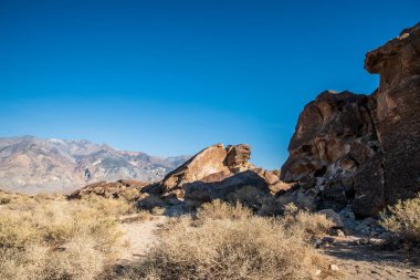 Owens Valley California 'da çöl kaya oluşumları ve uzak dağlar.