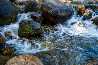  Kaliforniya 'nın dağlarındaki büyük kayaların etrafında akan çalkantılı beyaz sular.