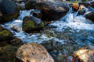  Kaliforniya 'nın dağlarındaki büyük kayaların etrafında akan çalkantılı beyaz sular.