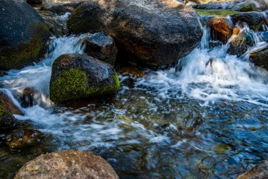  Kaliforniya 'nın dağlarındaki büyük kayaların etrafında akan çalkantılı beyaz sular.