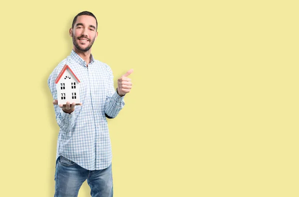 Concept of a young man of real-state holding a toy house