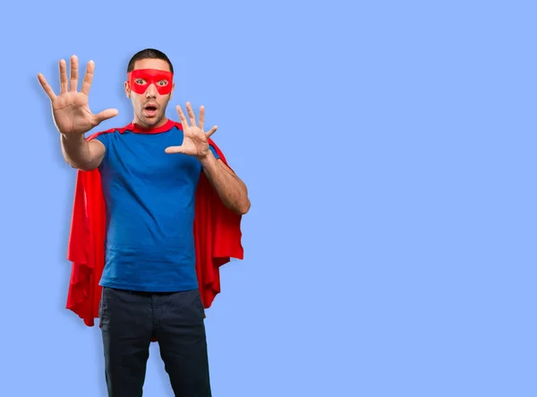 Scared superhero posing against blue background