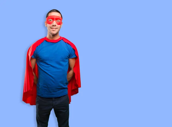 Happy superhero posing against blue background