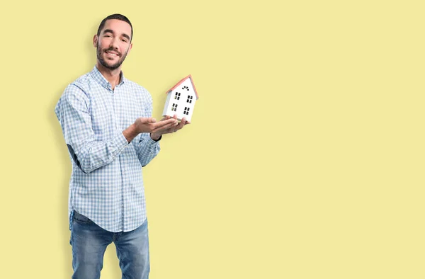 Concept of a young man of real-state holding a toy house