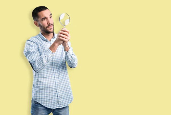 Worried young man with a magnifying glass