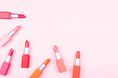 Renkli pastel rujlar pembe arkaplanda fotokopi alanı, güzellik ve makyaj konseptiyle düzenlenmiş.