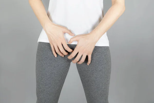 woman wore gray shorts put her hand on the genitalia area, Penis pain.Health-care,infection, incontinence,urinary, bladder,dysmenorrhea concept on gray background