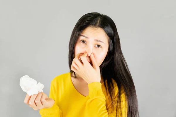 年轻的亚洲女人穿着黄色的衬衫 感冒了 擦拭着灰蒙蒙的背景上的污渍 保健观念 — 图库照片