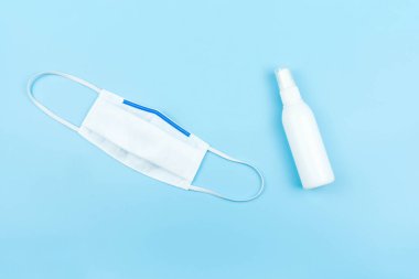 Tıbbi maske ve sprey alkol mavi arka planda izole edilmiş, sağlık hizmeti konsepti
