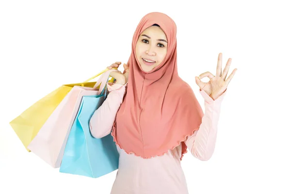 白い背景に隔離された伝統的な色のショッピングバッグを保持している幸せな美しい若いイスラム教徒アジアの女性 — ストック写真
