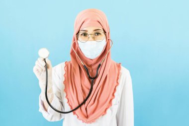 Medikal yüz maskesi, beyaz lateks tıp eldivenleri ve steteskopla mavi arka plan, sağlık konsepti olan Asyalı genç bayan doktor.
