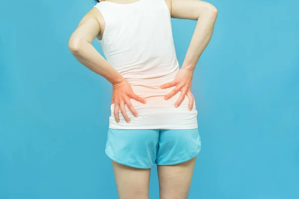 女人的下半身感觉背痛 穿着白衬衫站在孤立的蓝色背景上 手放在腰部 因为运动 疼痛的疾病感觉不舒服 阿切概念 — 图库照片
