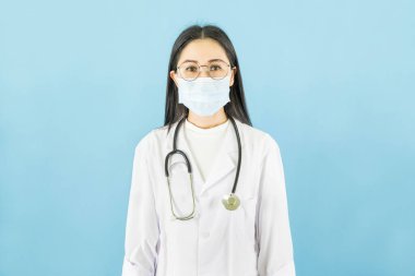 Tıbbi yüz maskesi, beyaz lateks tıp eldivenleri ve steteskopla mavi arka plan, sağlık konsepti olan zeki Asyalı kadın doktor.