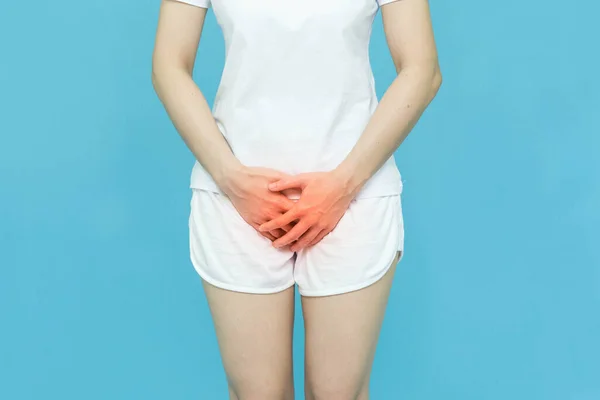 woman in white clothes put her hands on the genitalia area,hand on spot of ache and red mark, Penis pain or Itching urinary Health-care concept on blue background