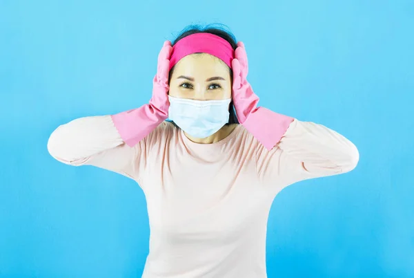 lady house wife maid in face mask,latex gloves on hands, crazy bad mood dirty messy flat wear headband pink shirt isolated blue color background
