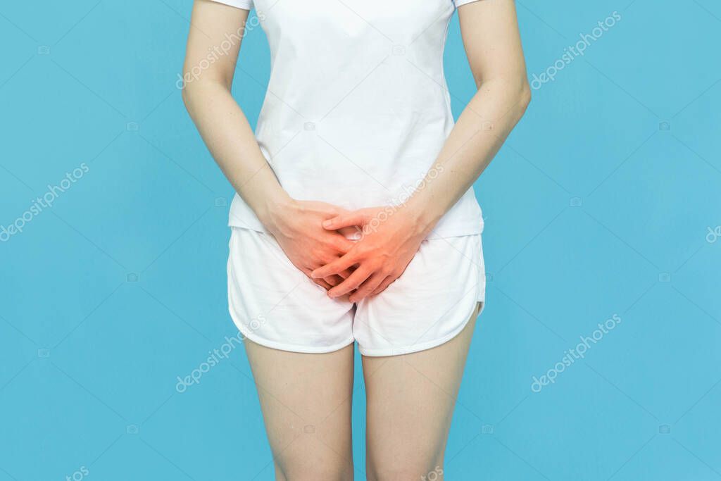 woman in white clothes put her hands on the genitalia area,hand on spot of ache and red mark, Penis pain or Itching urinary Health-care concept on blue background