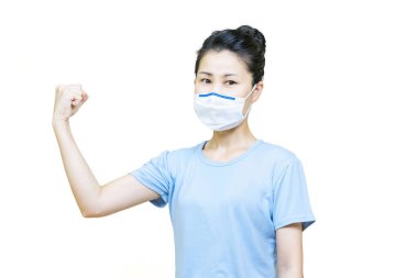 Mavi tişörtlü genç Asyalı kadın beyaz arka planda izole edilmiş sağlık maskesi takıyordu..