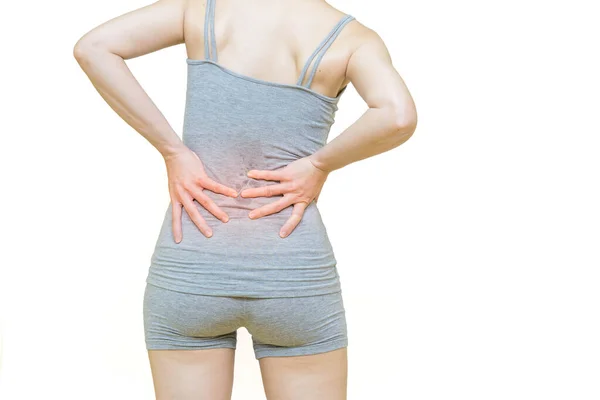 一位穿着灰色衣服的女性身材低矮 双手放在腰部疼痛部位 并在白色背景上标注出红肿 保健观念 — 图库照片