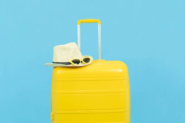 Yaz tatili, tatil ve seyahat kavramı. Sarı bavul ya da bagaj çantası. Güneş şapkası ve güneş gözlüğü.