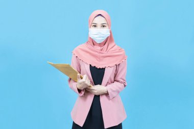 Geleneksel giysili, tıbbi maske takan, Asyalı güzel bir iş kadını portresi ve mavi arka planda izole edilmiş siyah bir takım elbise.