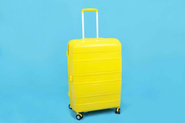 Sarı bavul ya da bavul mavi arka planda izole edilmiş, seyahat kavramı
